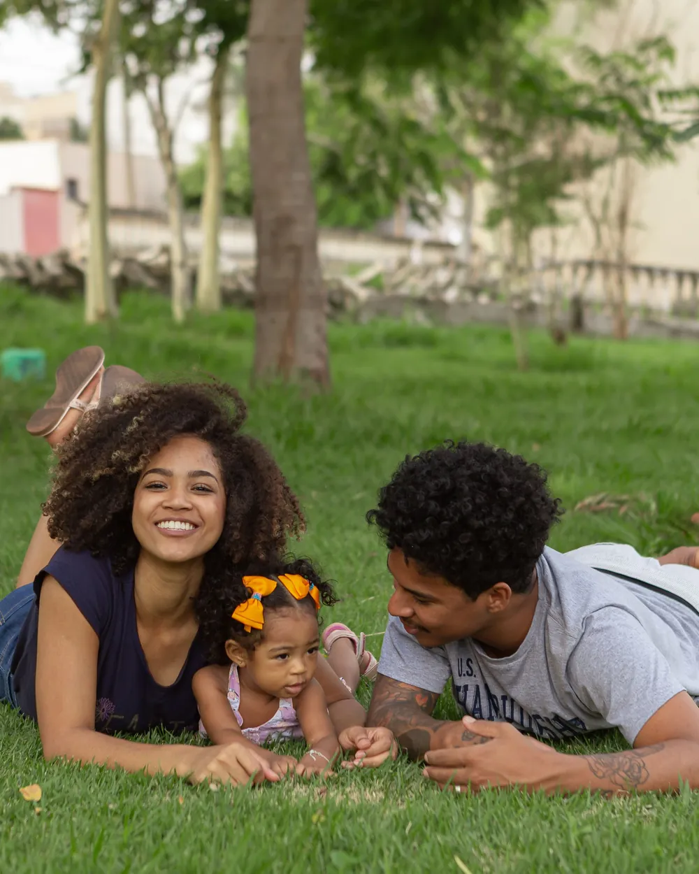 A young family lying together on the grass in a park