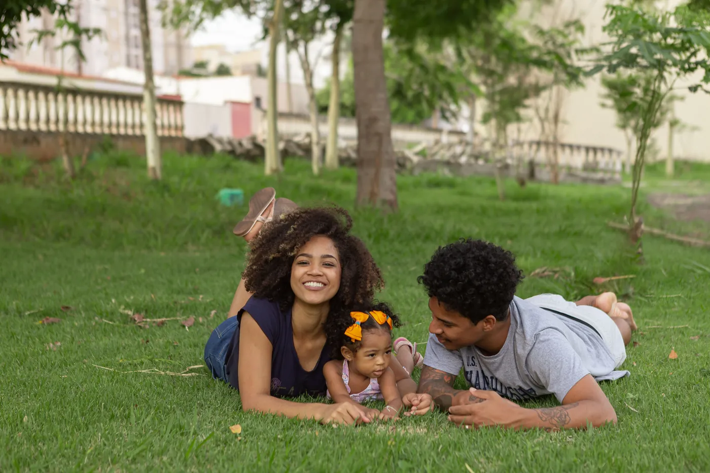 A young family lying together on the grass in a park