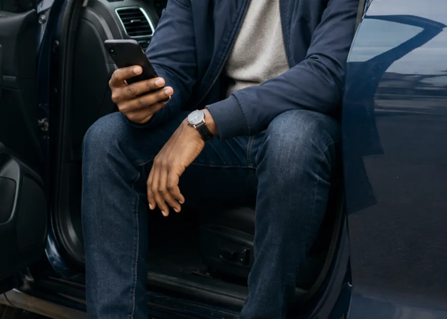 A phone in hand in the doorway of a car